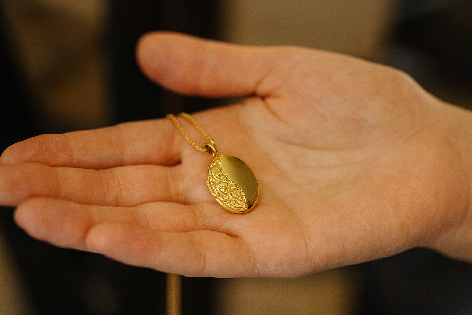 Gold necklace with a pendant held in a hand against a blurred background